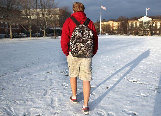 Student with backpack walking across campus in snow